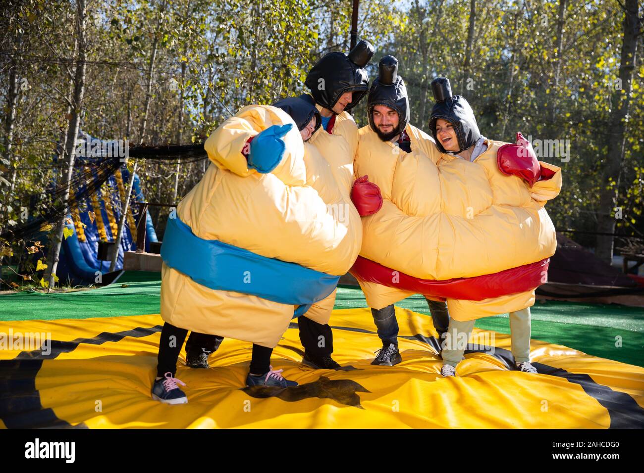Portrait of happy adult friends having fun posing in inflatable sumo