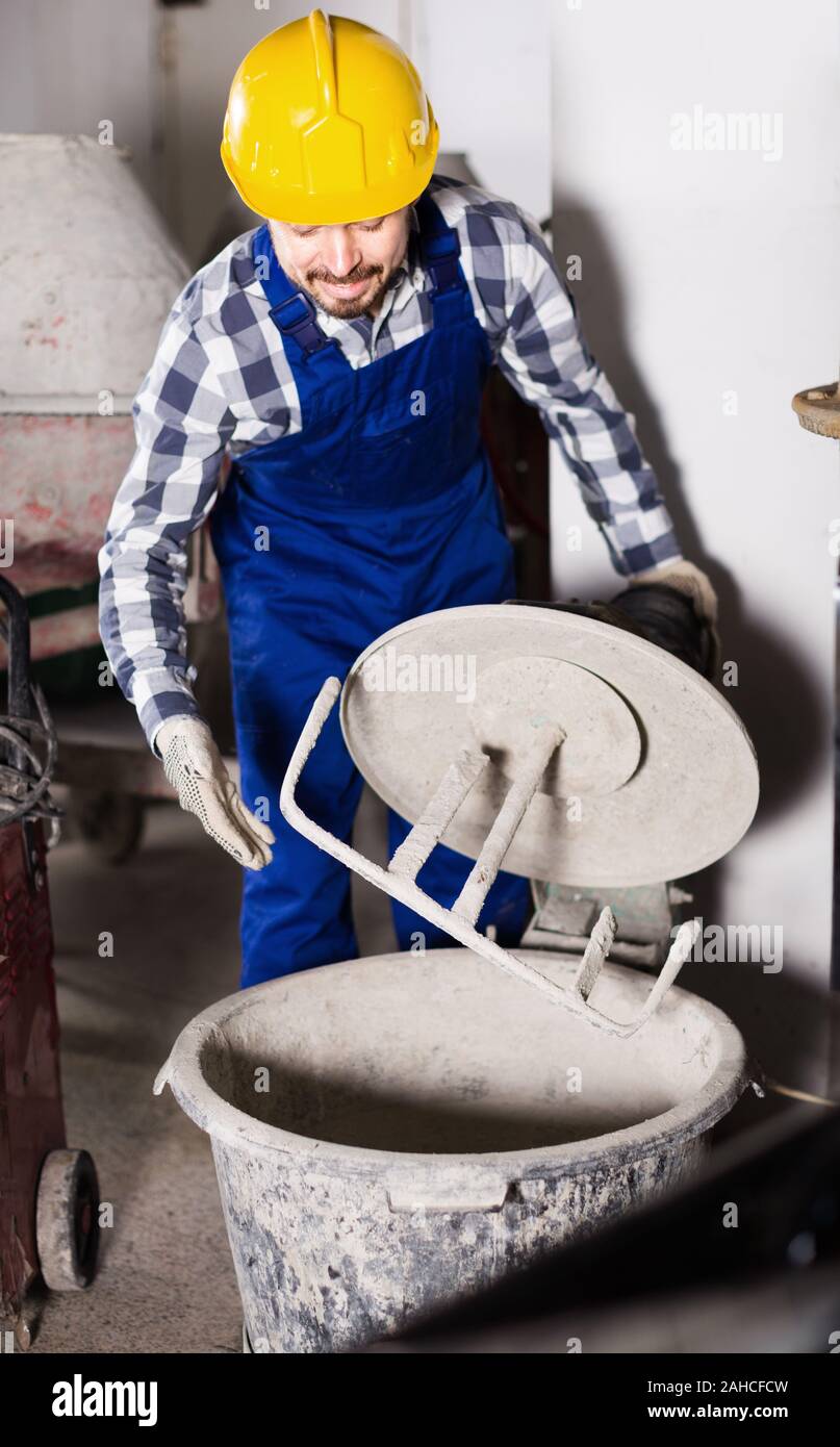 Young smiling man using concrete mixer for construction work at workplace Stock Photo