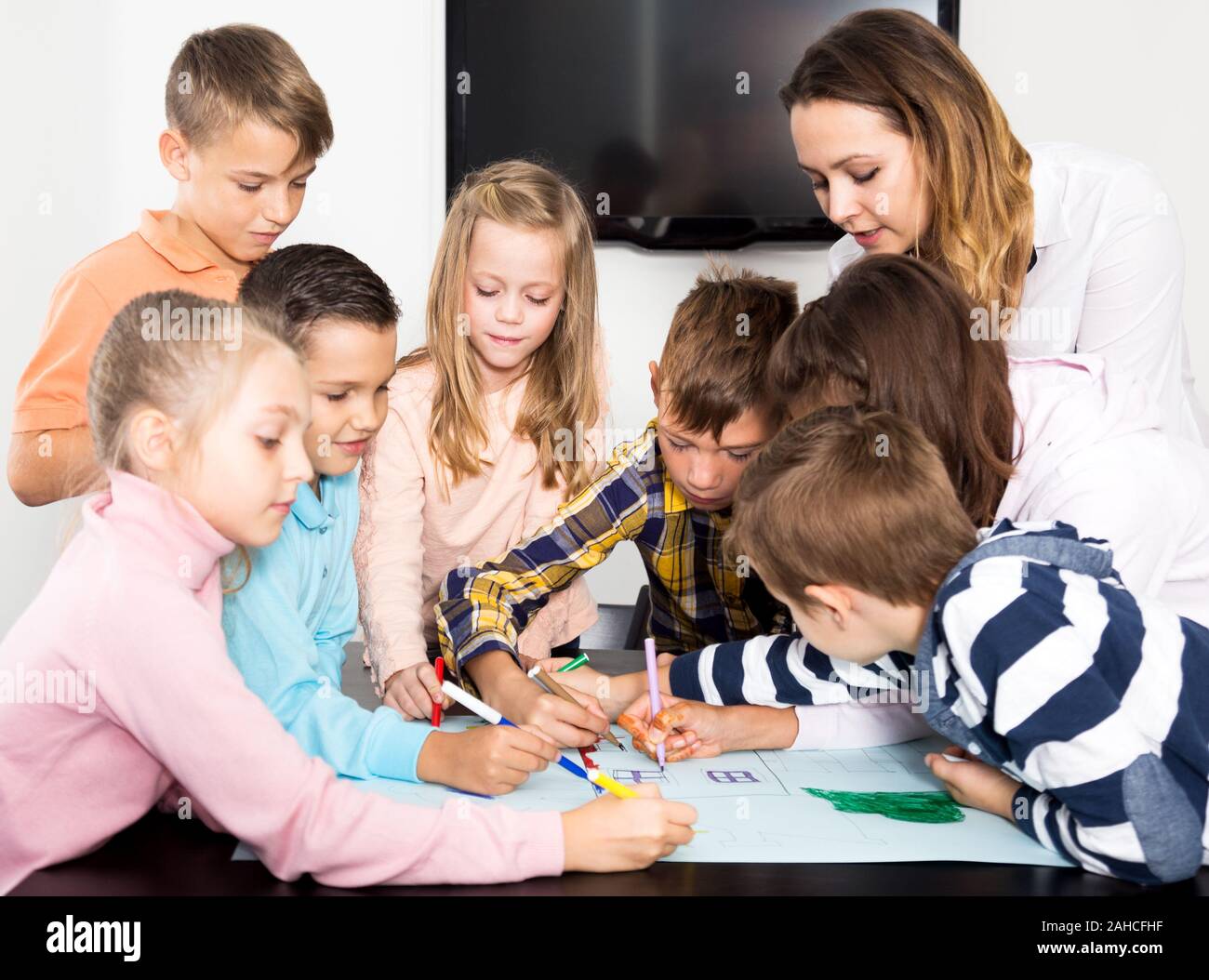 Beautiful team of elementary age children and female teacher drawing on ...