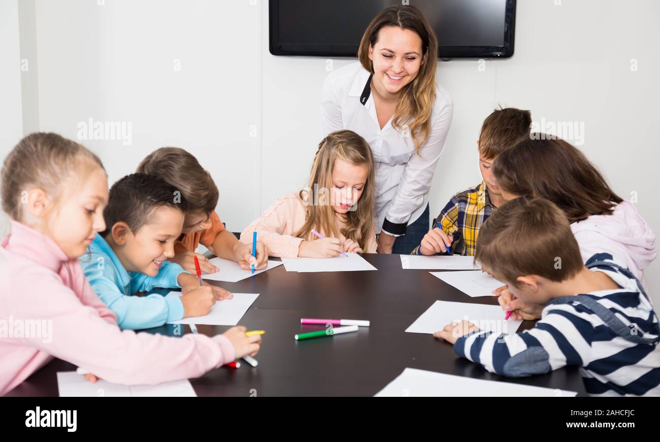 serious little children with teacher drawing in classroom on the lesson ...