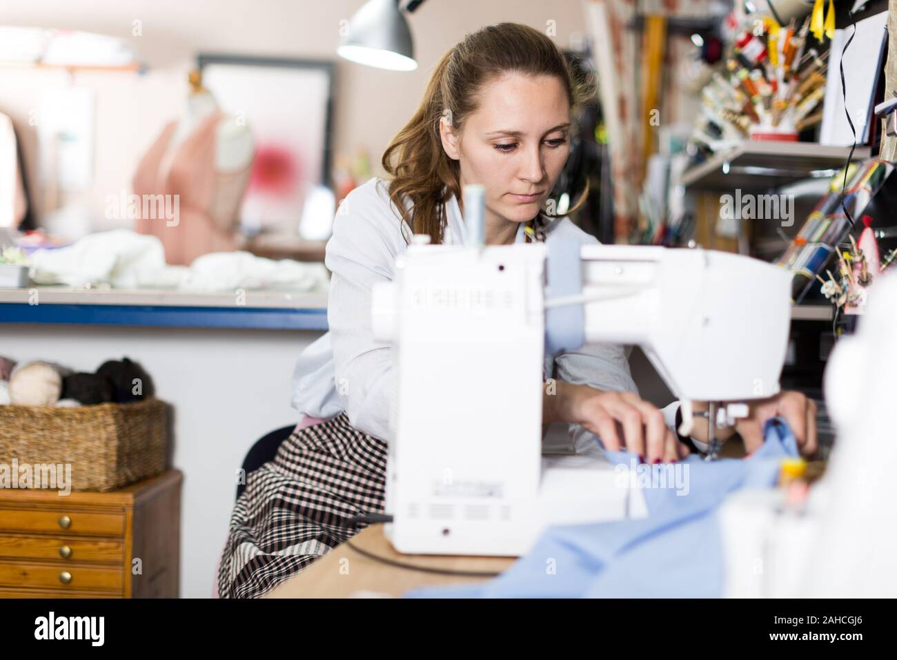 Young woman sewer working with modern sewing machine at workshop Stock Photo