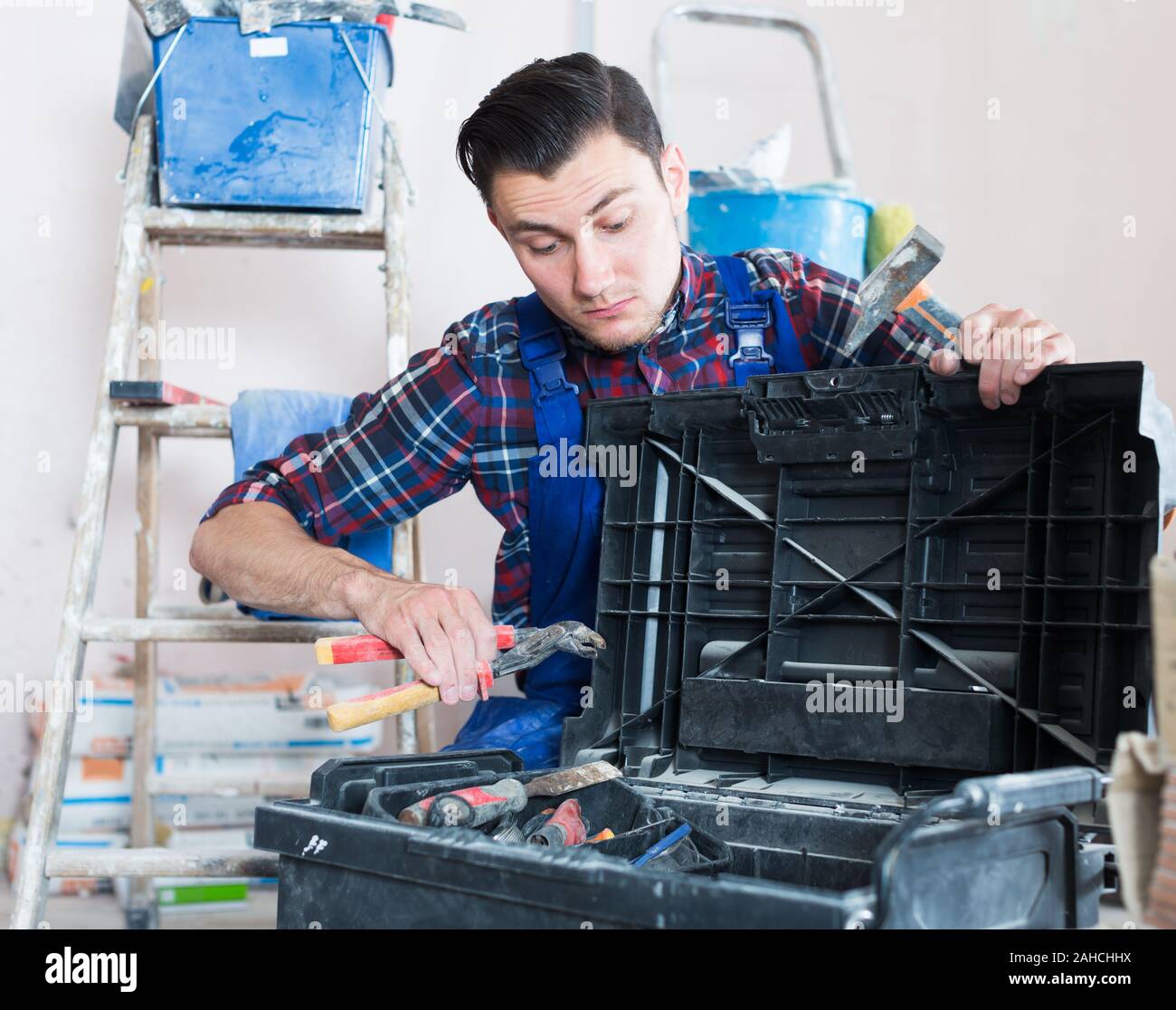 Worker repairing room and looking for necessary tool in toolbox Stock Photo