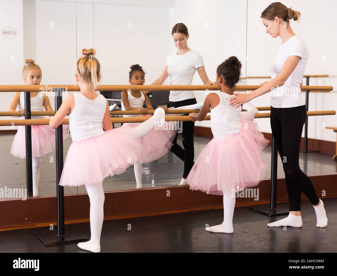 Female ballet trainer teaching two little girls near ballet barre in  dancing hall Stock Photo - Alamy