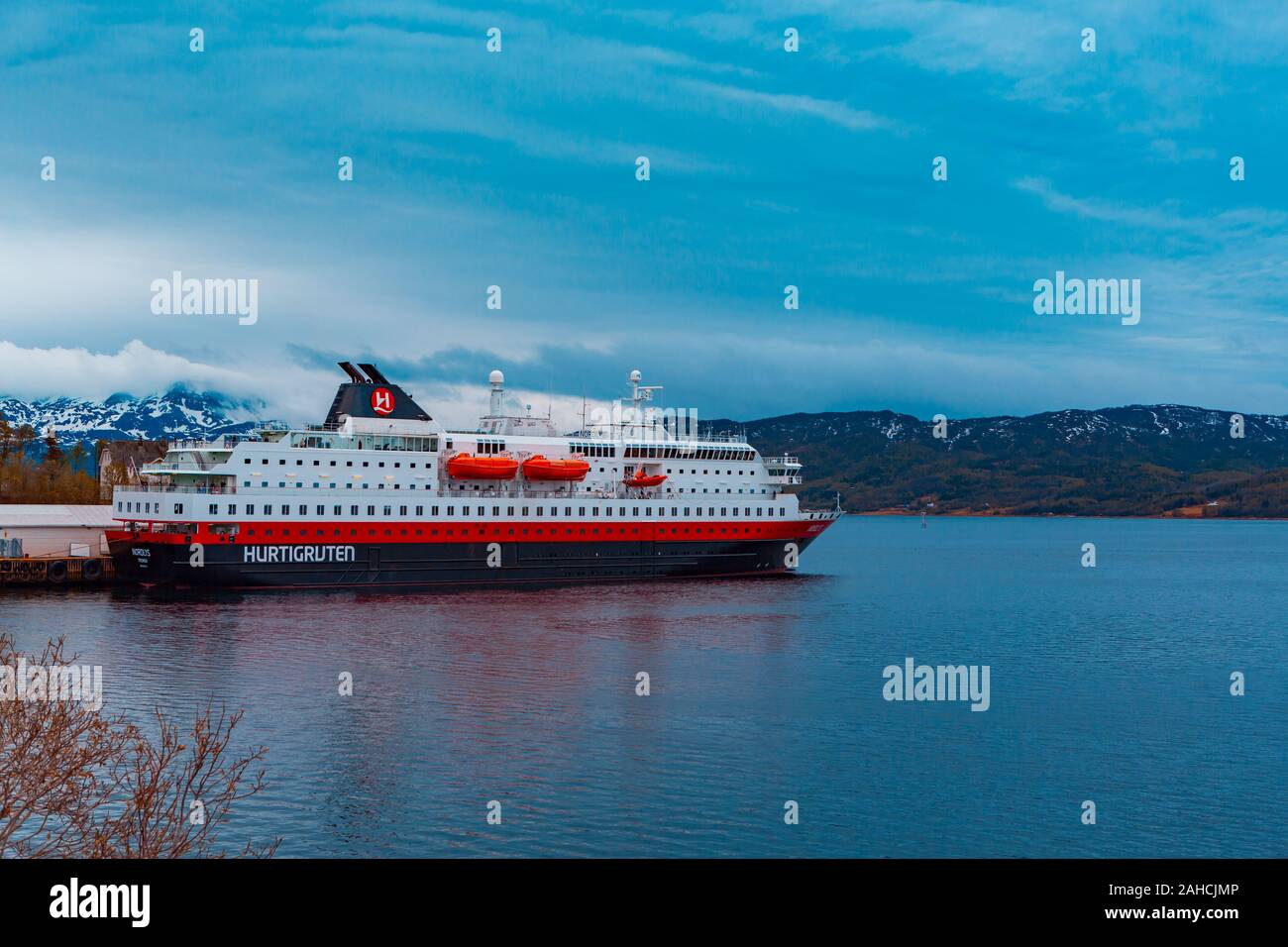 FINNSNES, NORWAY - CIRCA MAY, 2018:  The Hurtigruten ferry in front of Senja Island landscape. Finnsnes town in Norway. Stock Photo
