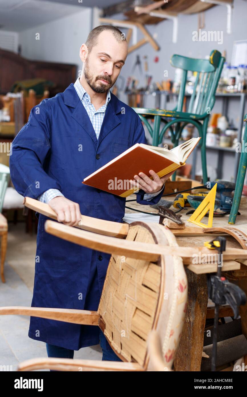 Craftsman looking at album in furniture restoration Stock