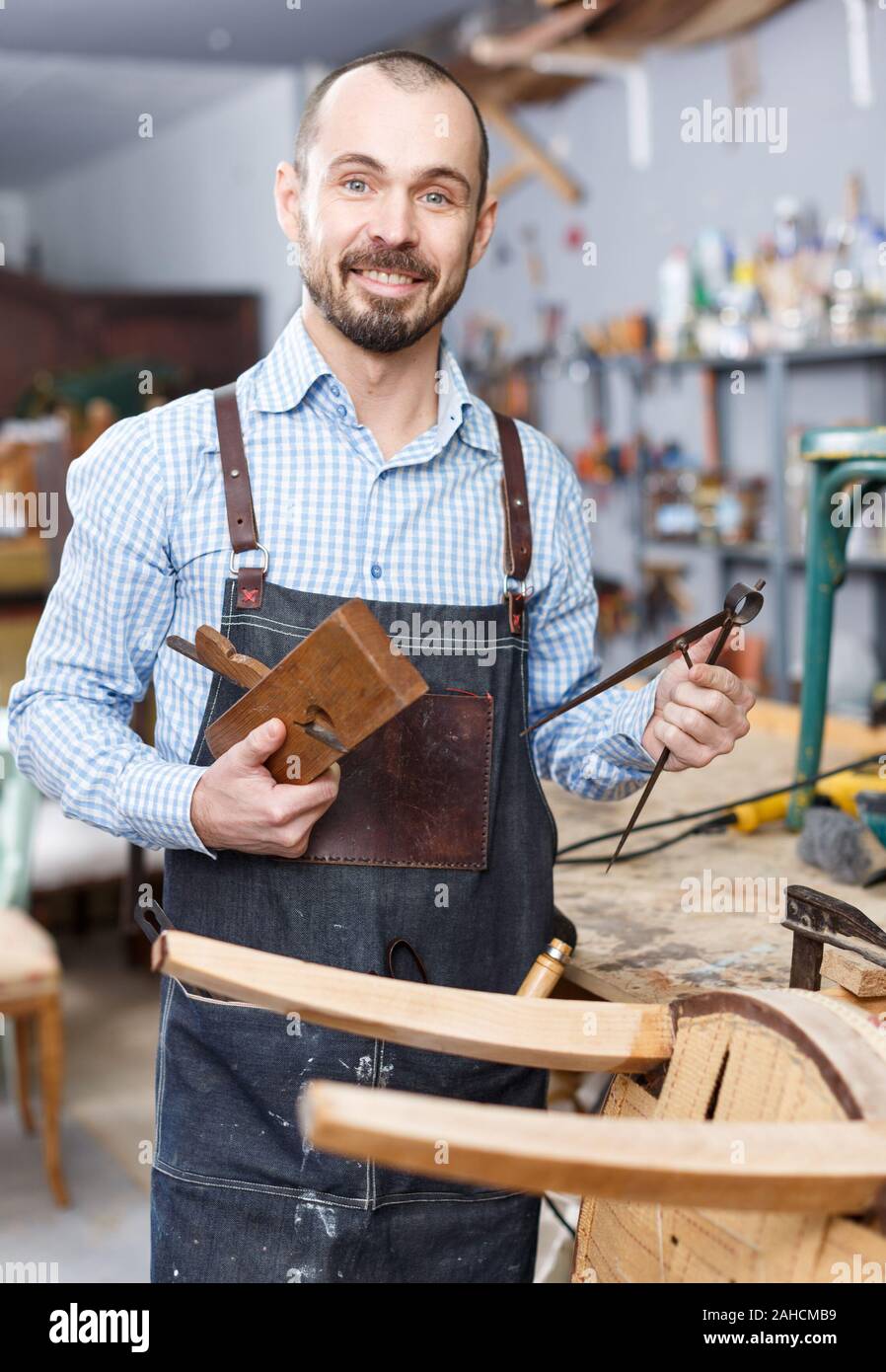 Cheerful Craftsman With Carpentry Tools Posing In Furniture