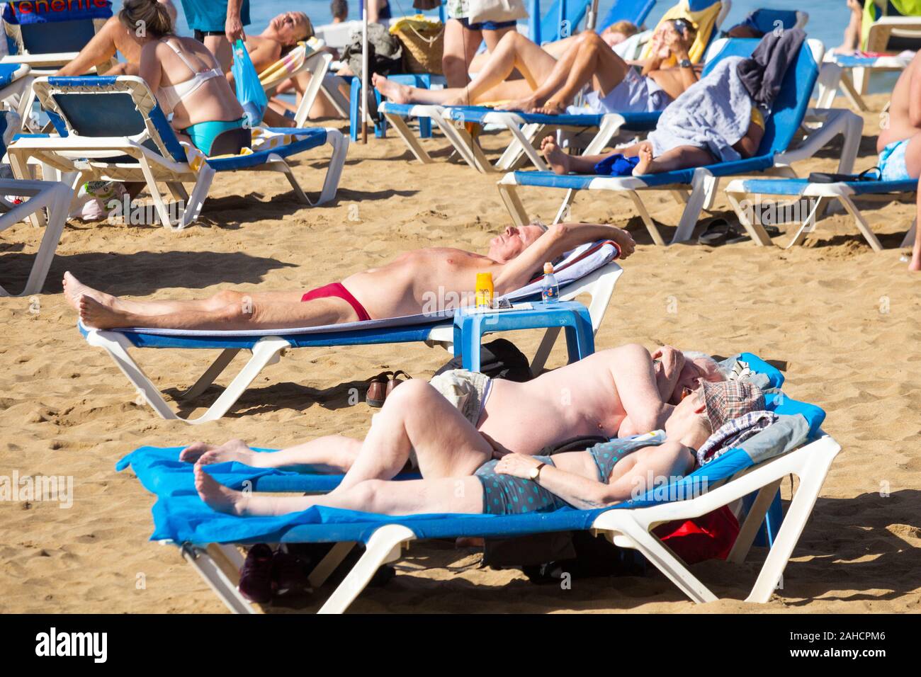 Tourists sunbathing on city beach in Las Palmas on Gran Canaria. A popular winter sun destination for many Brits. Stock Photo
