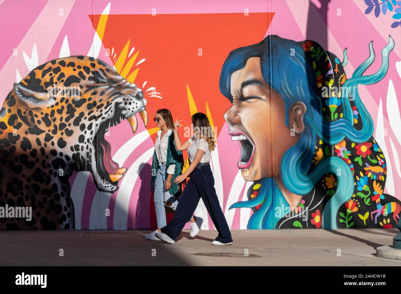 Girlfriends walk past murals in downtown El Paso, Texas Stock Photo