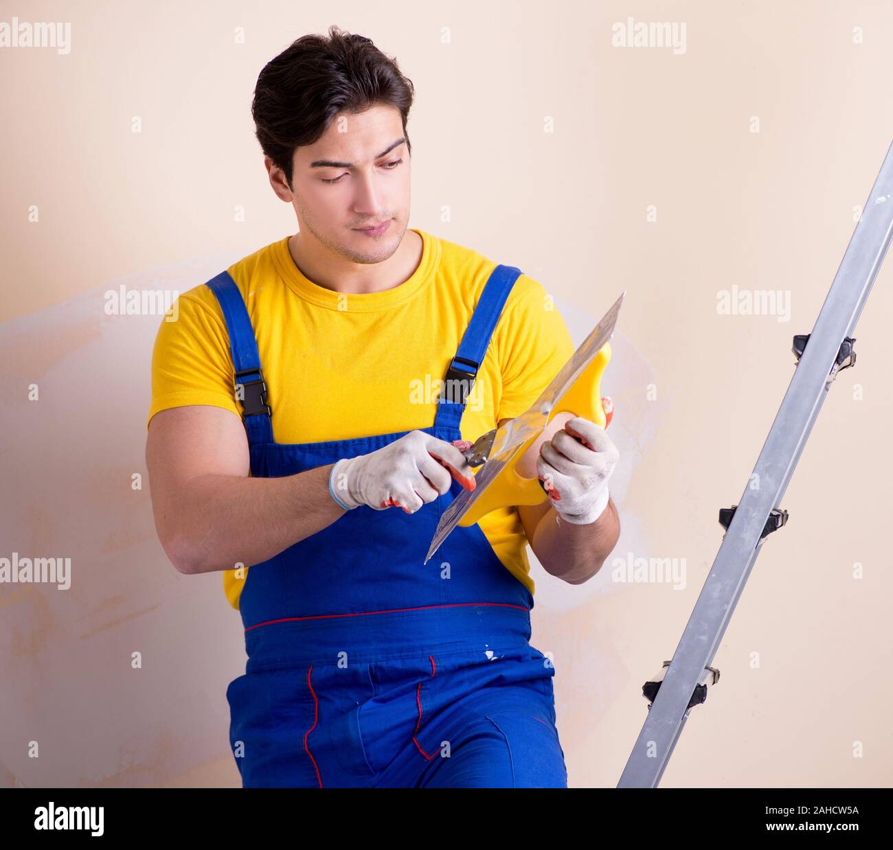 The young contractor employee applying plaster on wall Stock Photo