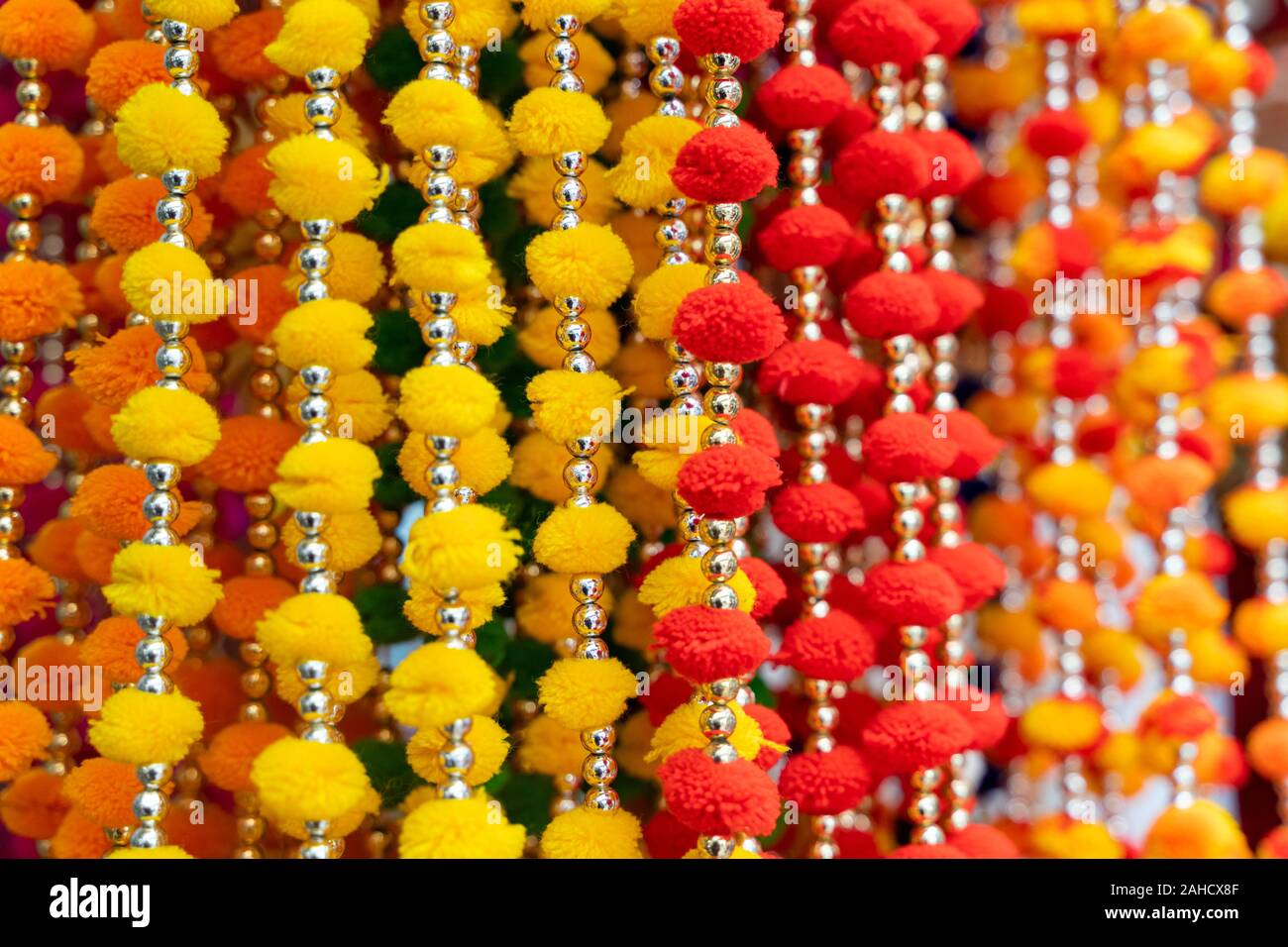 Colorful hanging Indian decorations for sale in colors of yellow, orange and red in Old Delhi market in India Stock Photo