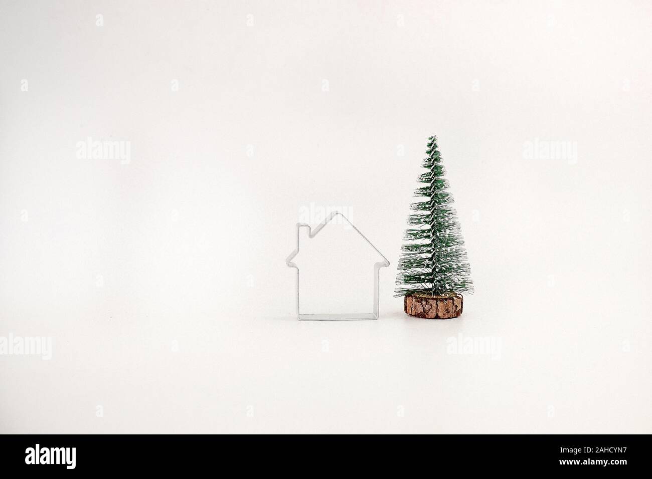 miniature snowcovered Christmas tree and a simple house isolated on
