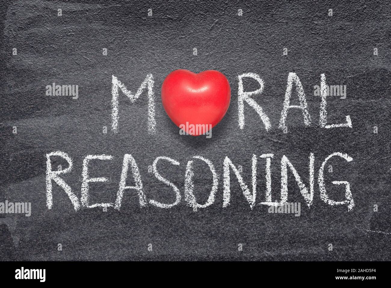 moral reasoning phrase handwritten on chalkboard with red heart symbol instead of O Stock Photo