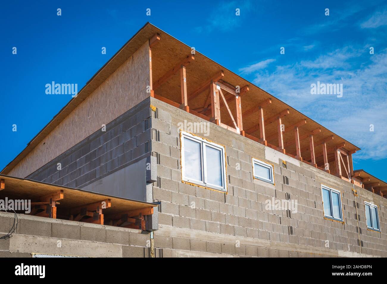 Roof construction - installation of wooden beams at house construction site. Building details with wood, timber and metal holders Stock Photo