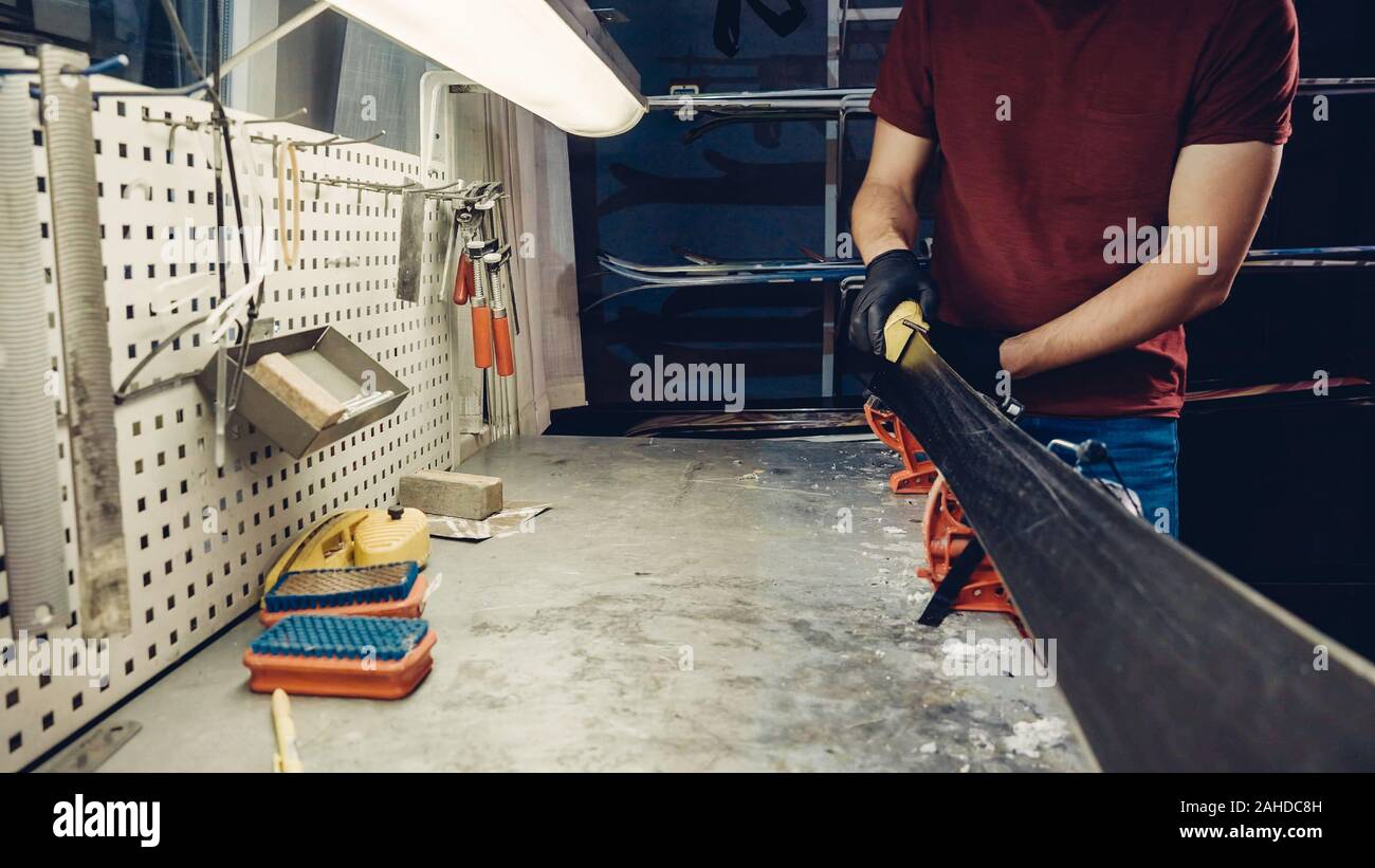 Male worker of ski service doing sharpening and repair of skis