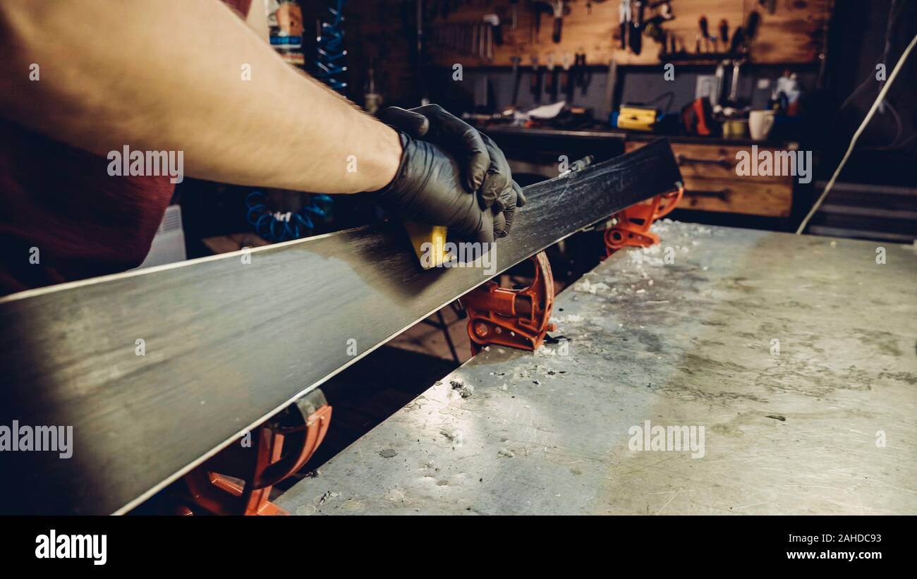 Male worker of ski service doing sharpening and repair of skis