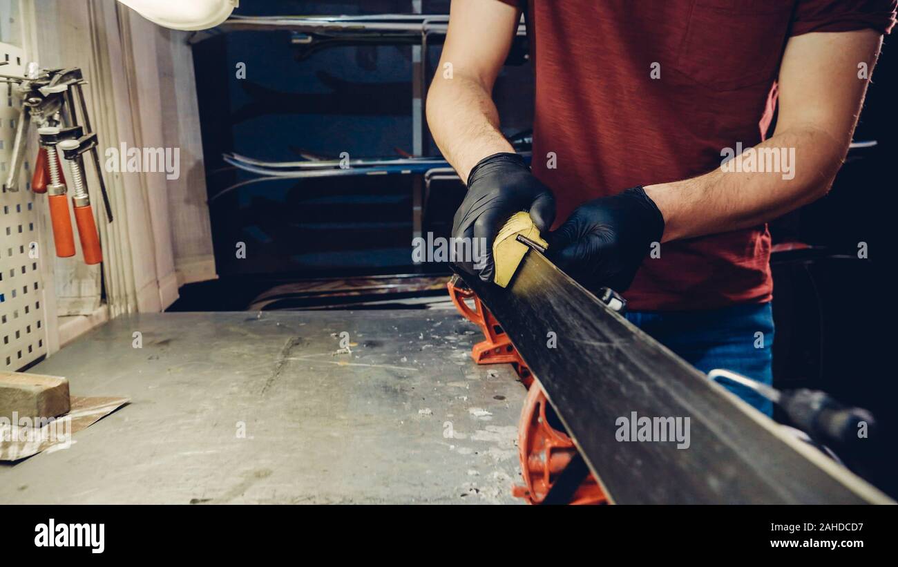 Male worker of ski service doing sharpening and repair of skis