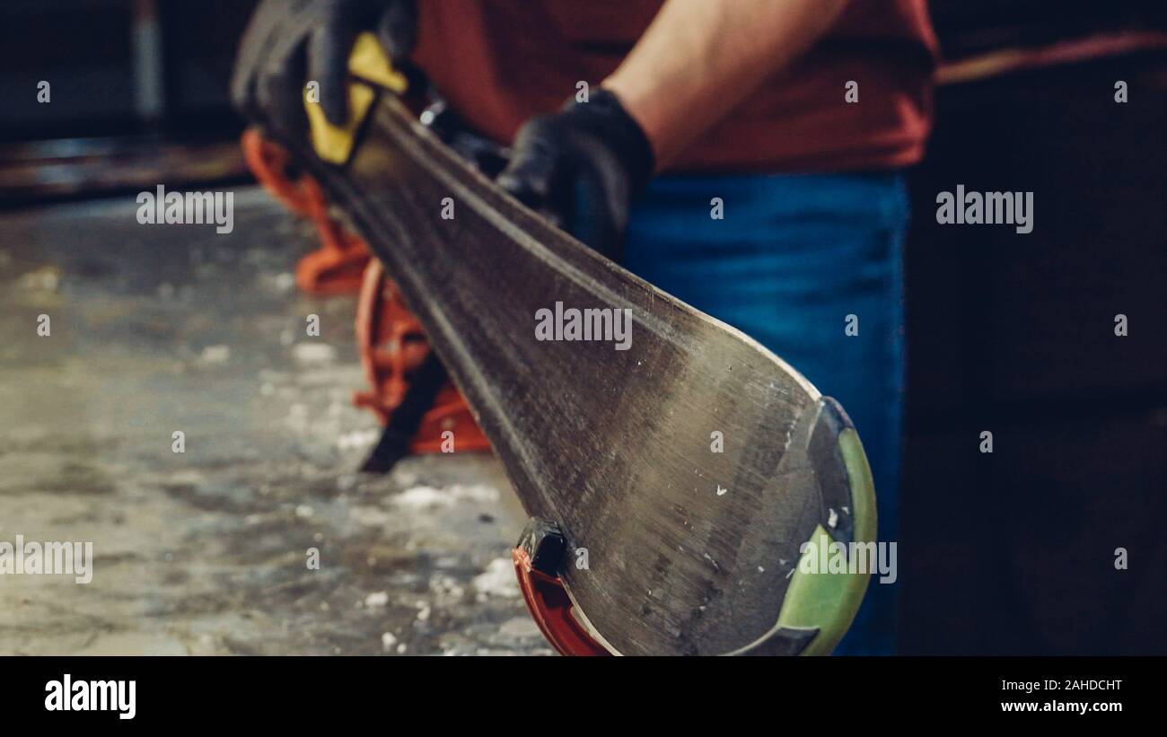 Male worker of ski service doing sharpening and repair of skis