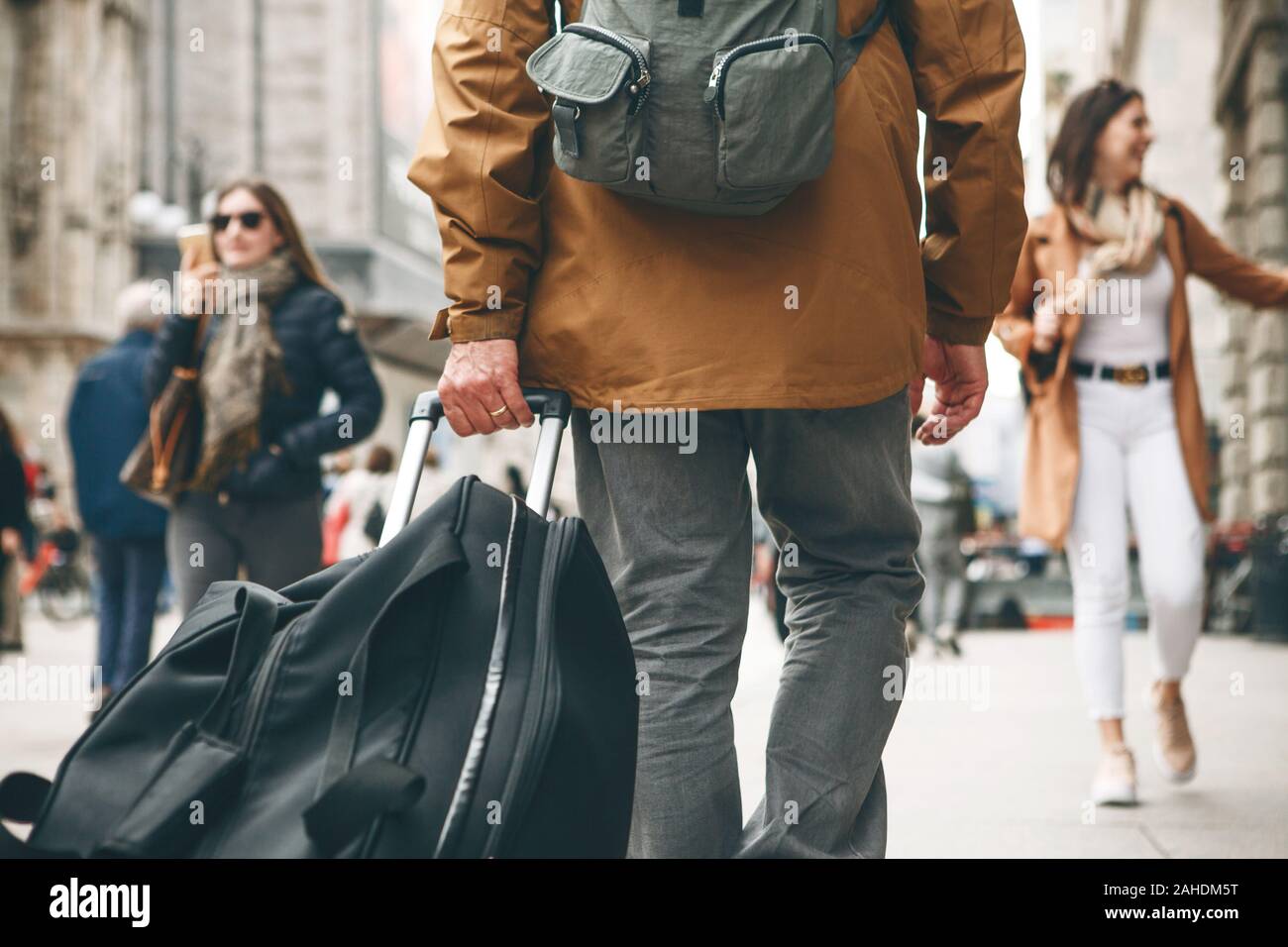 A tourist with a backpack and a suitcase is walking along a street in