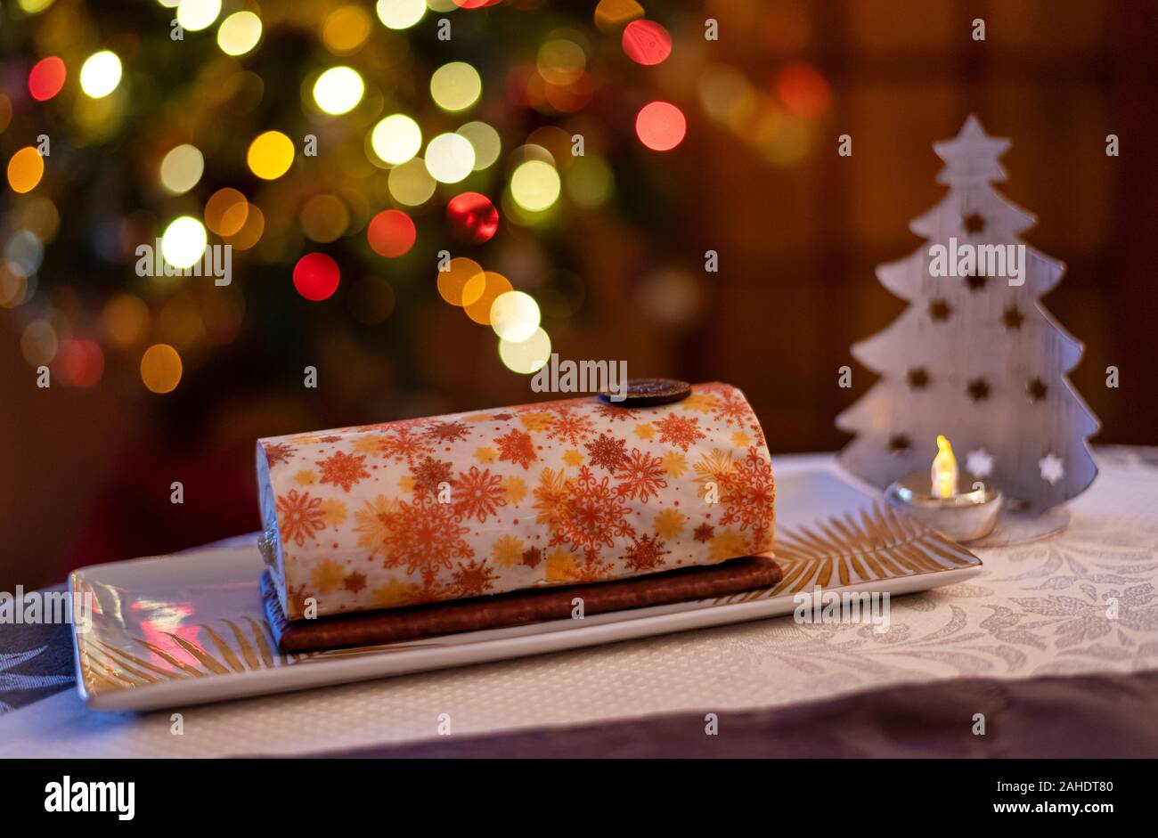 Yule log roll cake for Christmas decorated with magnificent patterns with a colorful bokeh background. Stock Photo