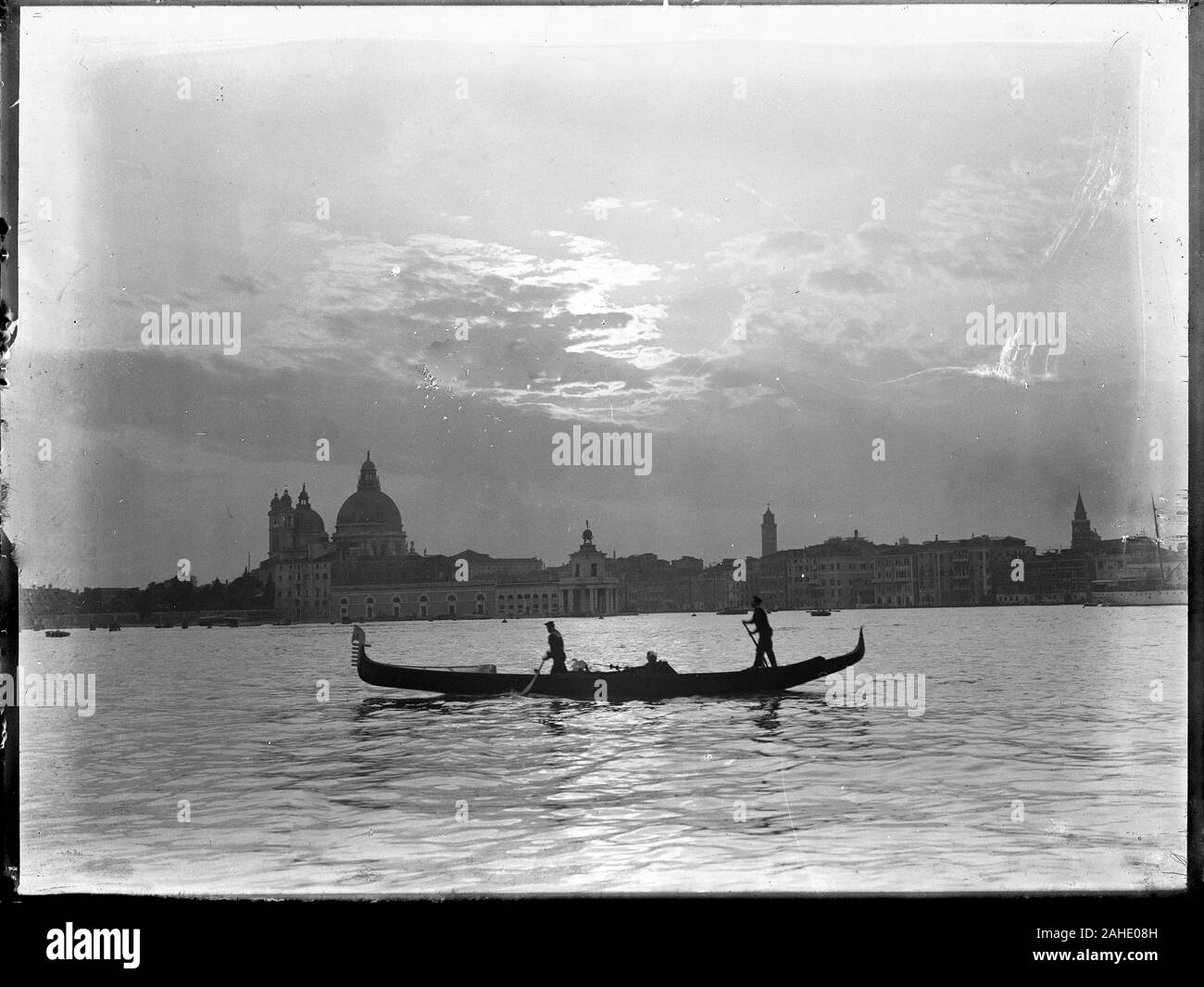 Black and white waterfront view of the Santa Maria della Salute church with a typical gondola in the foreground. The picture is a copy from a dry glass photograph from the 1910s contained in the Herry W. Schaefer Ottoman collection. Stock Photo