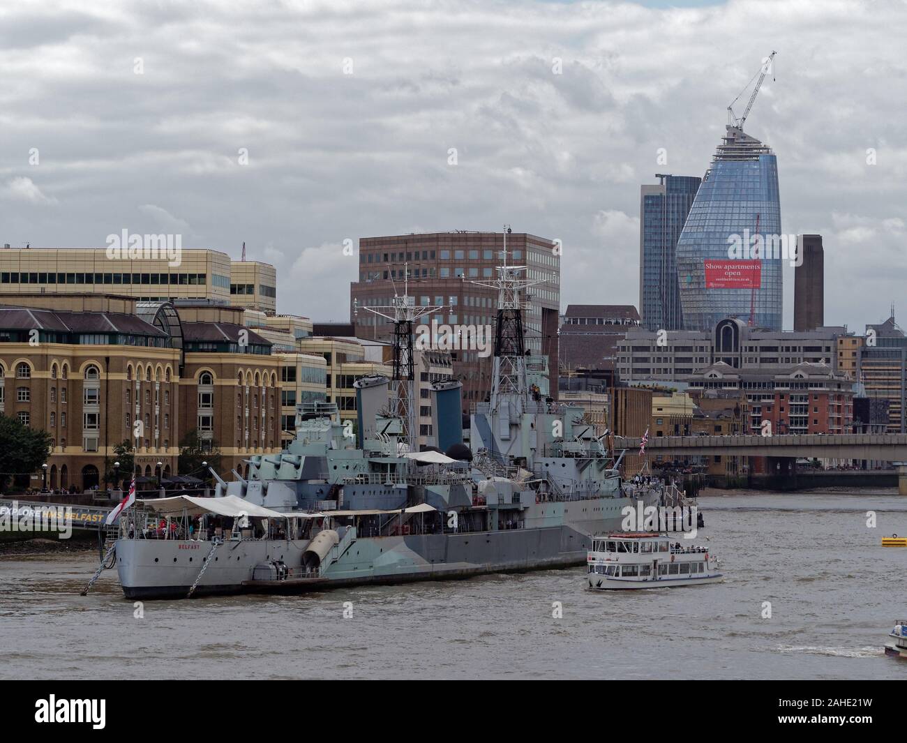 Museum ship light cruiser HMS Belfast on Thames River in front of Hay's Galleria in Southwark, with London Bridge and skyscrapers in the background. Stock Photo