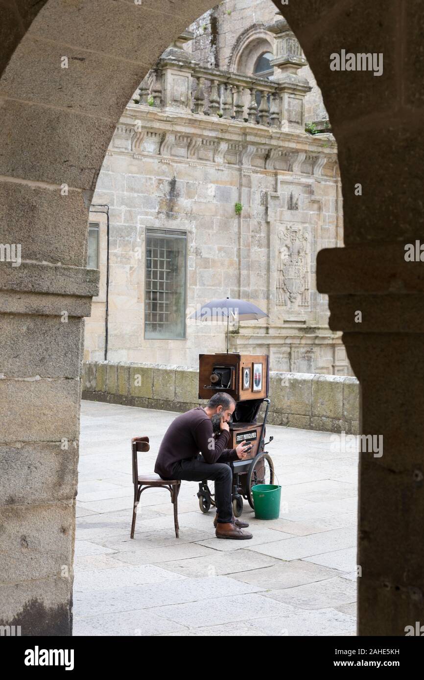 A street photographer with an old-fashioned view camera waits for subjects at Praza da Inmaculada in Santiago de Compostela, Spain. The city is the te Stock Photo