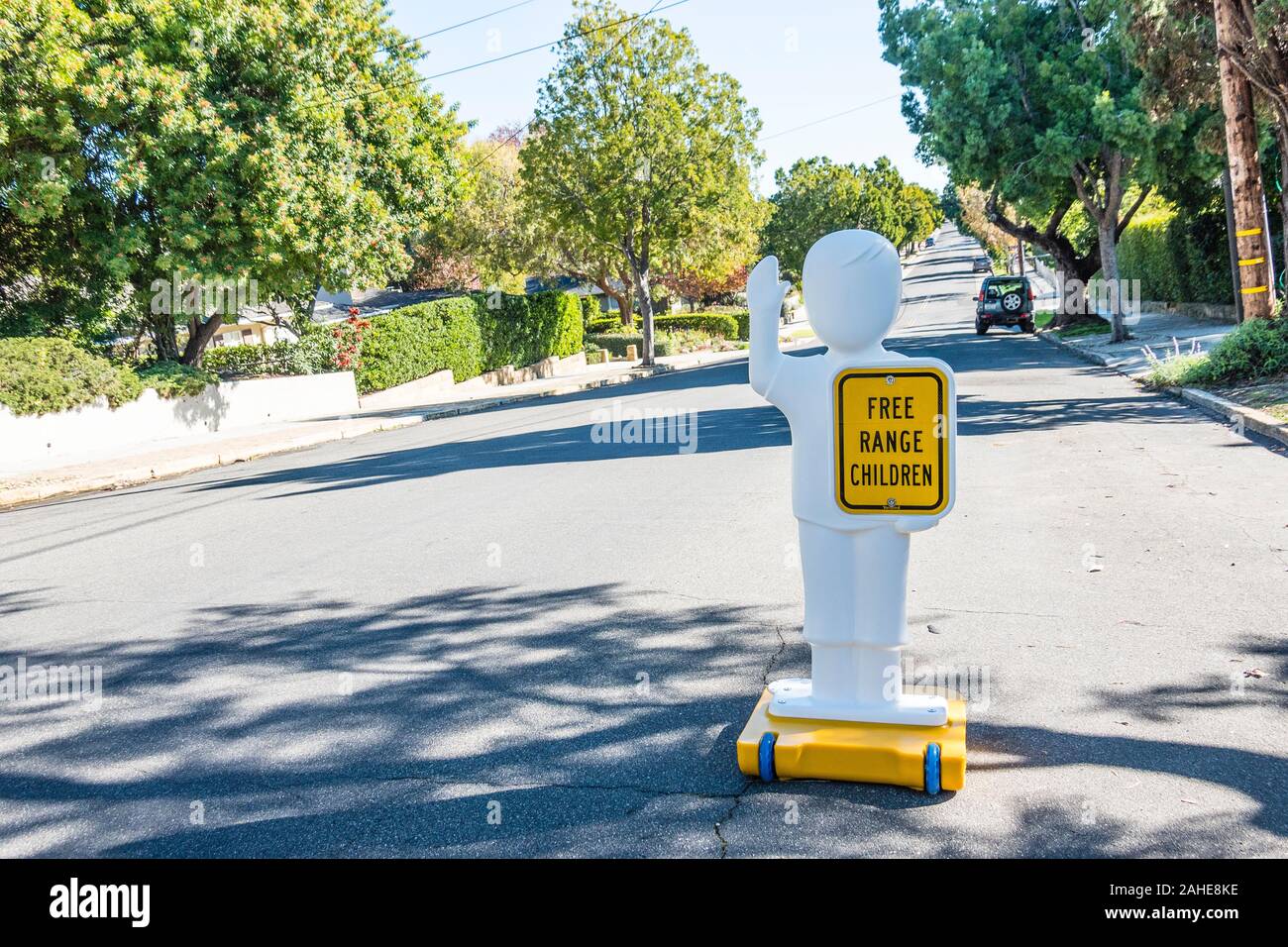 A very humorous sign in the street in front of a house with chiildren that states 'free range children' on a human-like figure to alert drivers. Stock Photo