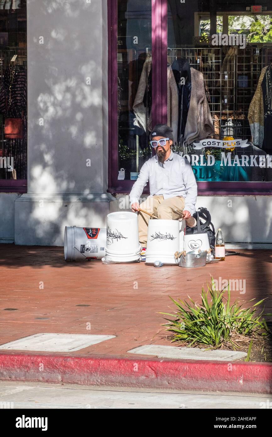 A street drummer, wearing a Fu Manchu, using white plastic 5 gallon buckets for his drum set. Stock Photo