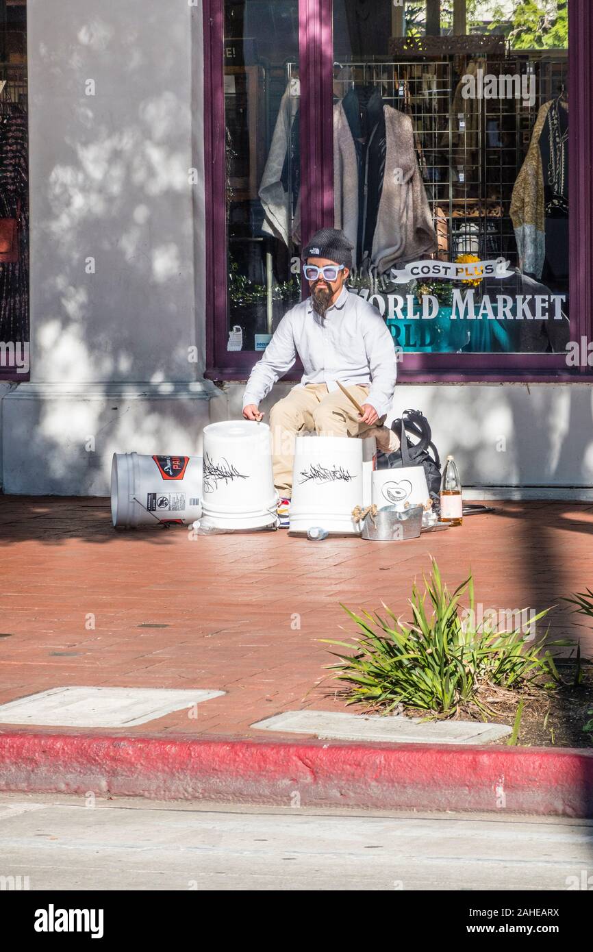 A street drummer, wearing a Fu Manchu, using white plastic 5 gallon buckets for his drum set. Stock Photo
