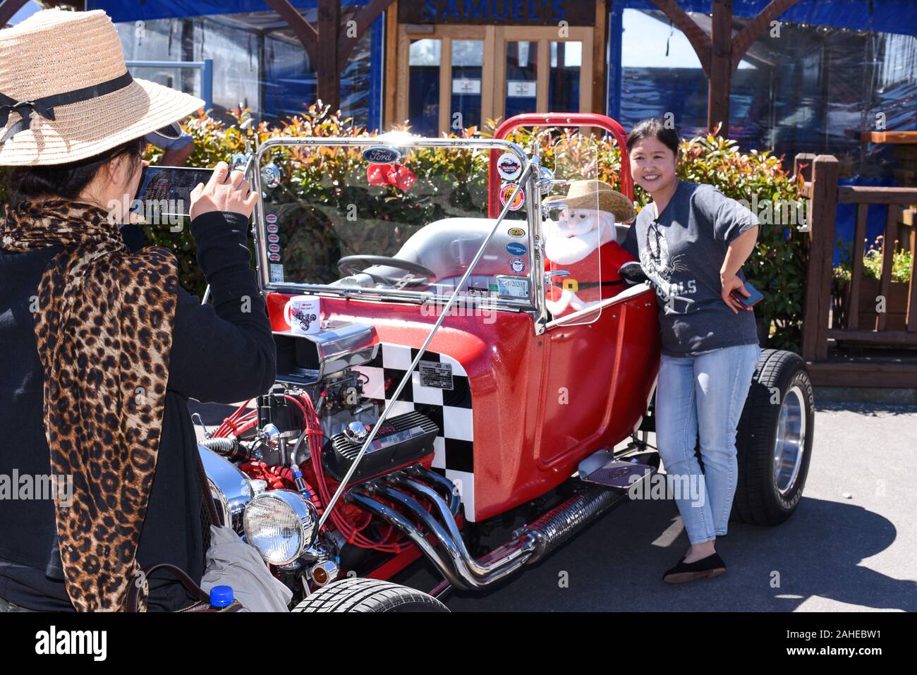 Methven, New Zealand. 28th Dec 2019. Posing for a selfie with a Santa Claus in a car at a gathering of hot rods and other custom cars on the southern island of New Zealand Stock Photo