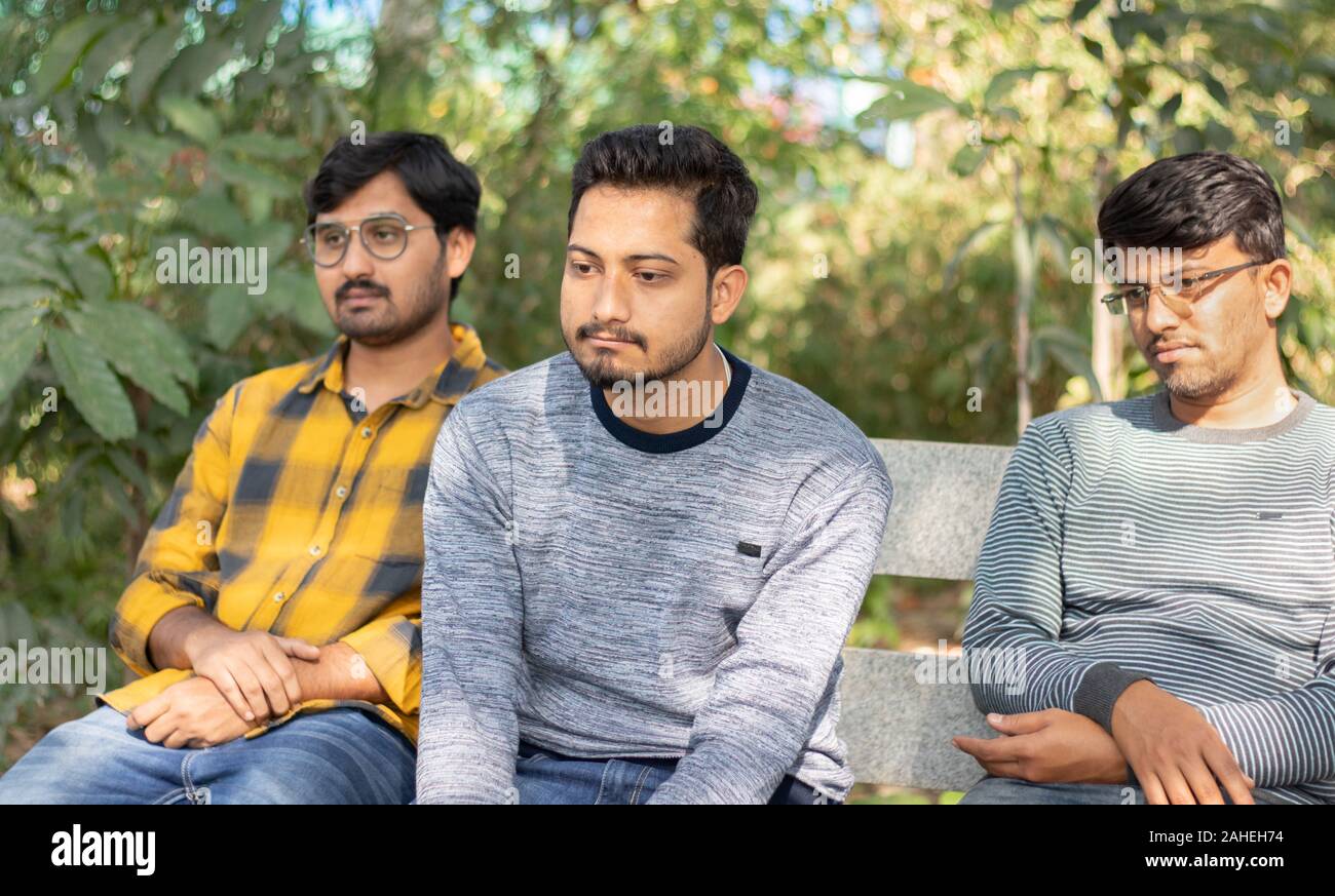 Three bored looking friends on table at park - Concept of boredom, lack of communication and fight between friends Stock Photo