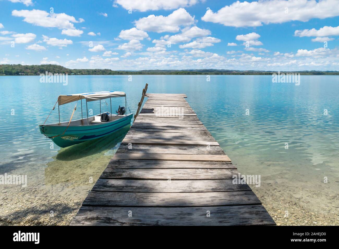 Boat at a wooden dock at lake Itza with turquoise water, El Remate, Peten, Guatemala Stock Photo