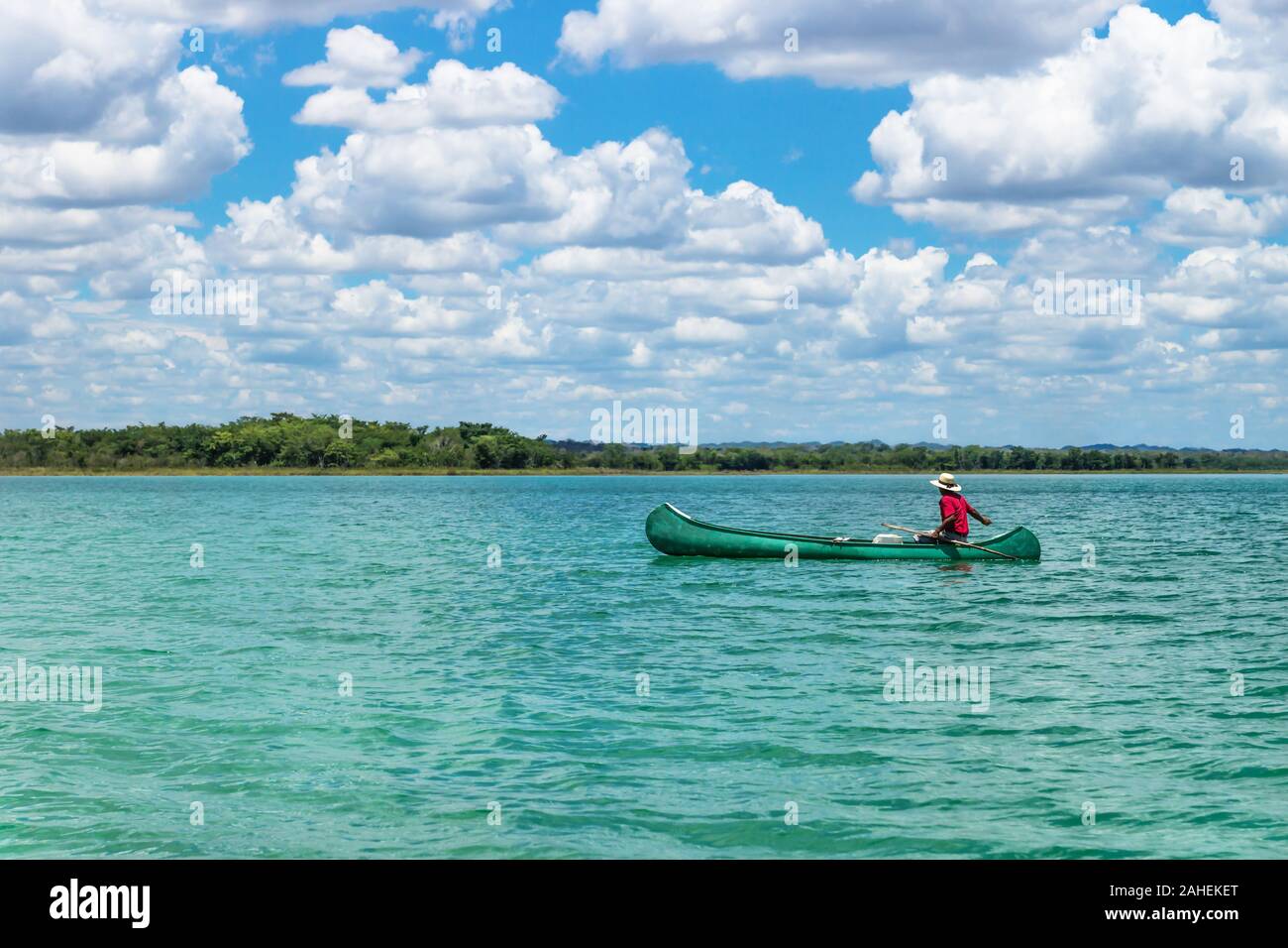 El Remate, Peten, Guatemala - 29 May 2019: Fisherman in canoe boat in turquoise colored lake Itza with sunny cloud sky Stock Photo