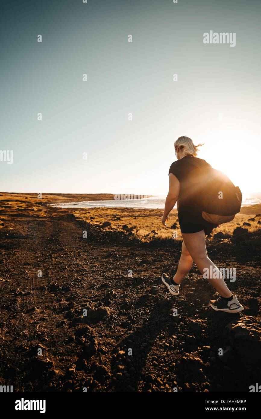 Women hikes during sunrise next to the Sea Stock Photo