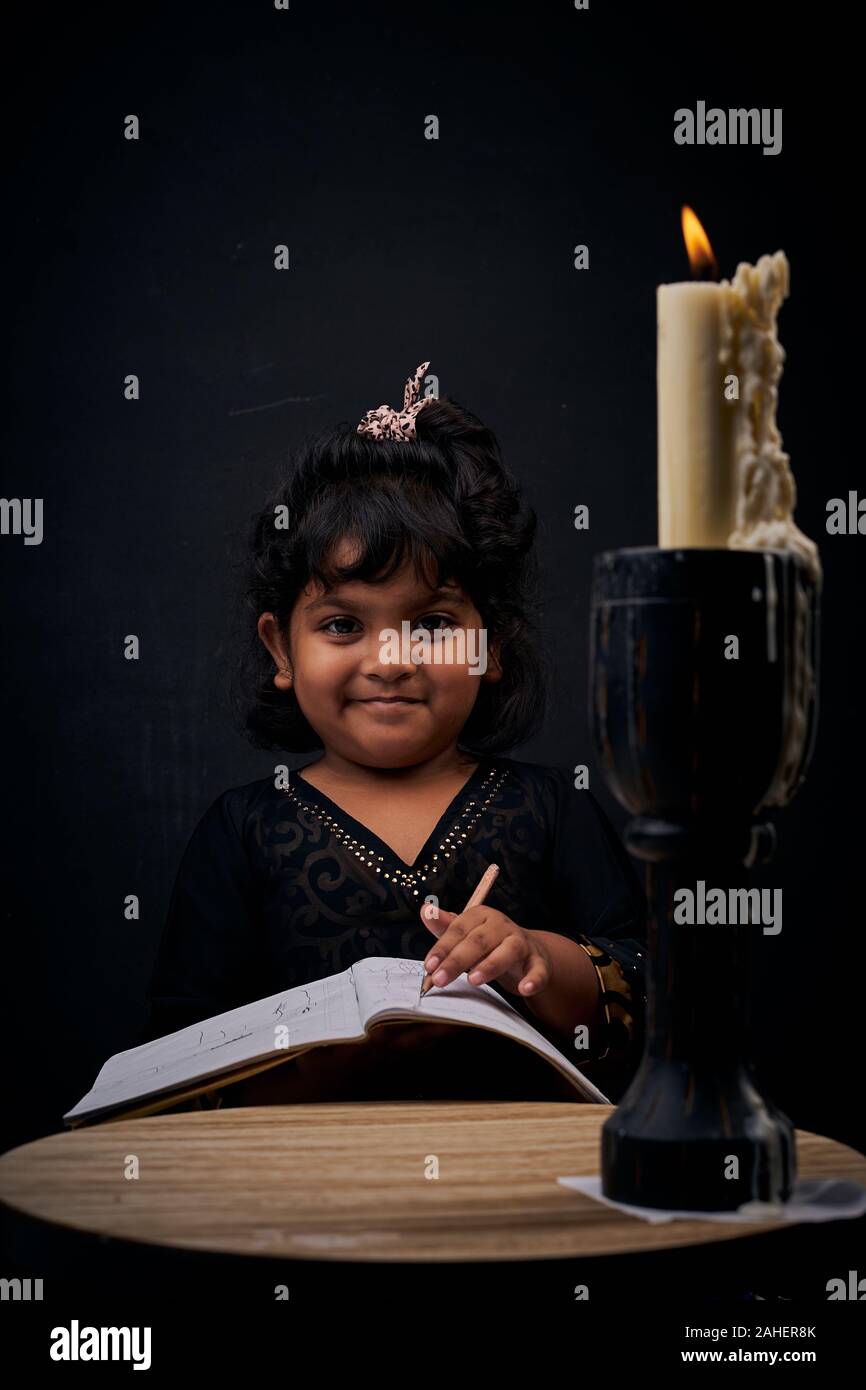 Cute little girl studying under illuminated candle light Stock Photo Alamy