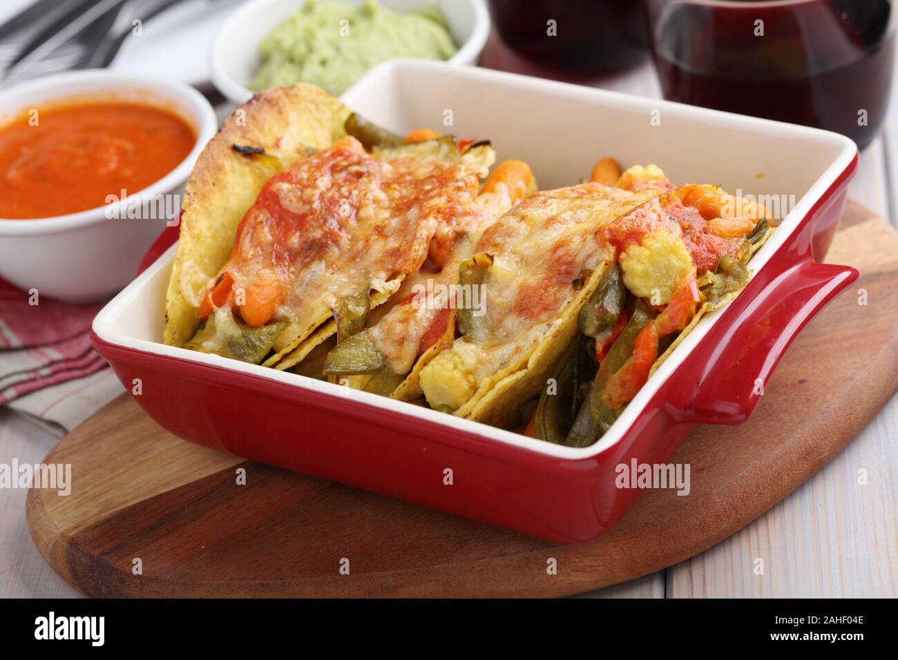 Vegetarian tacos with cheese, guacamole, salsa, and red wine on a rustic table Stock Photo