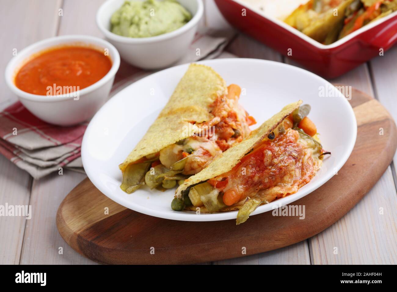 Vegetarian tacos with cheese, guacamole, and salsa on a rustic table Stock Photo