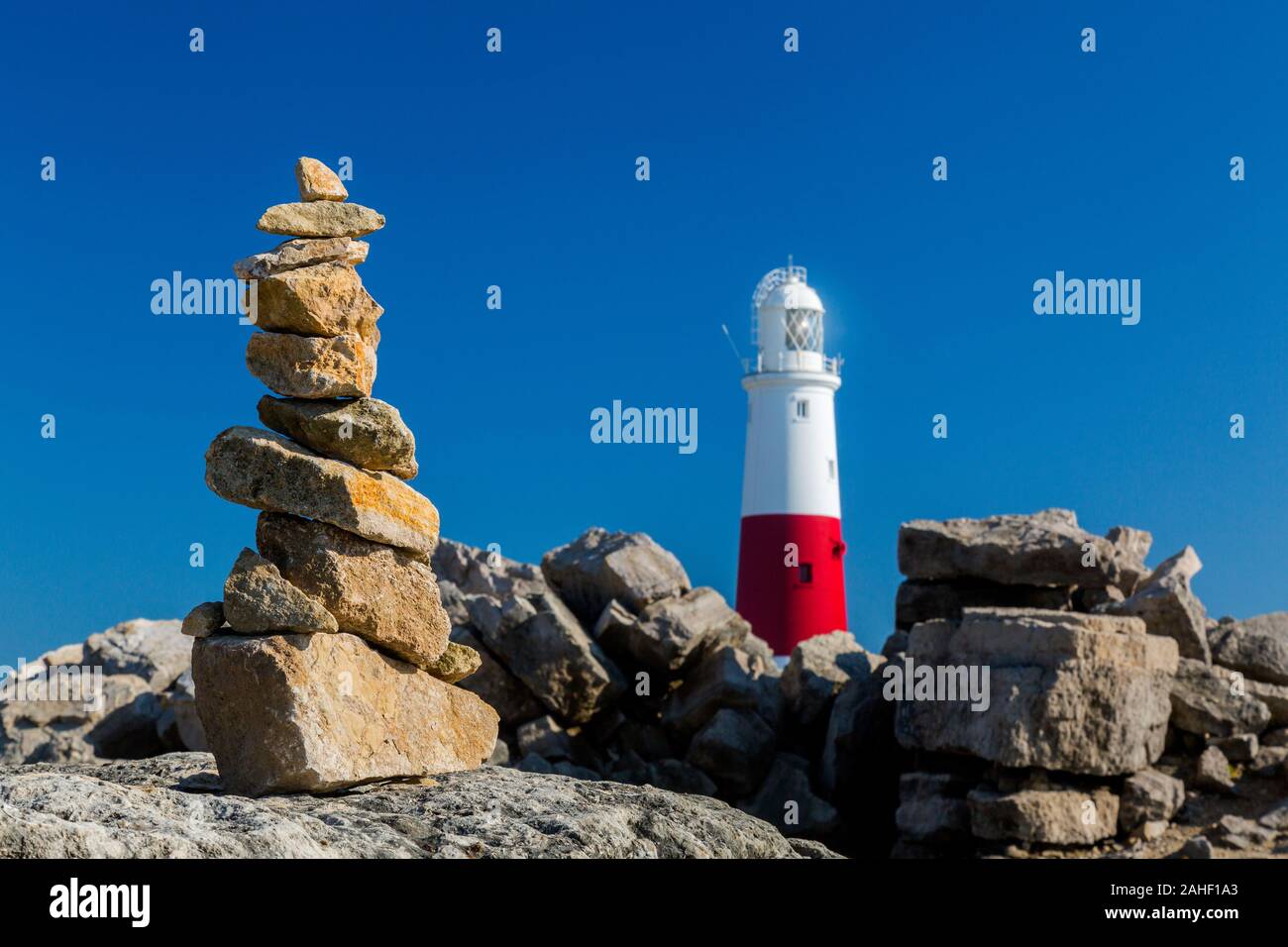 A pile of balancing stones and the lighthouse at Portland Bill, Dorset, England, UK Stock Photo