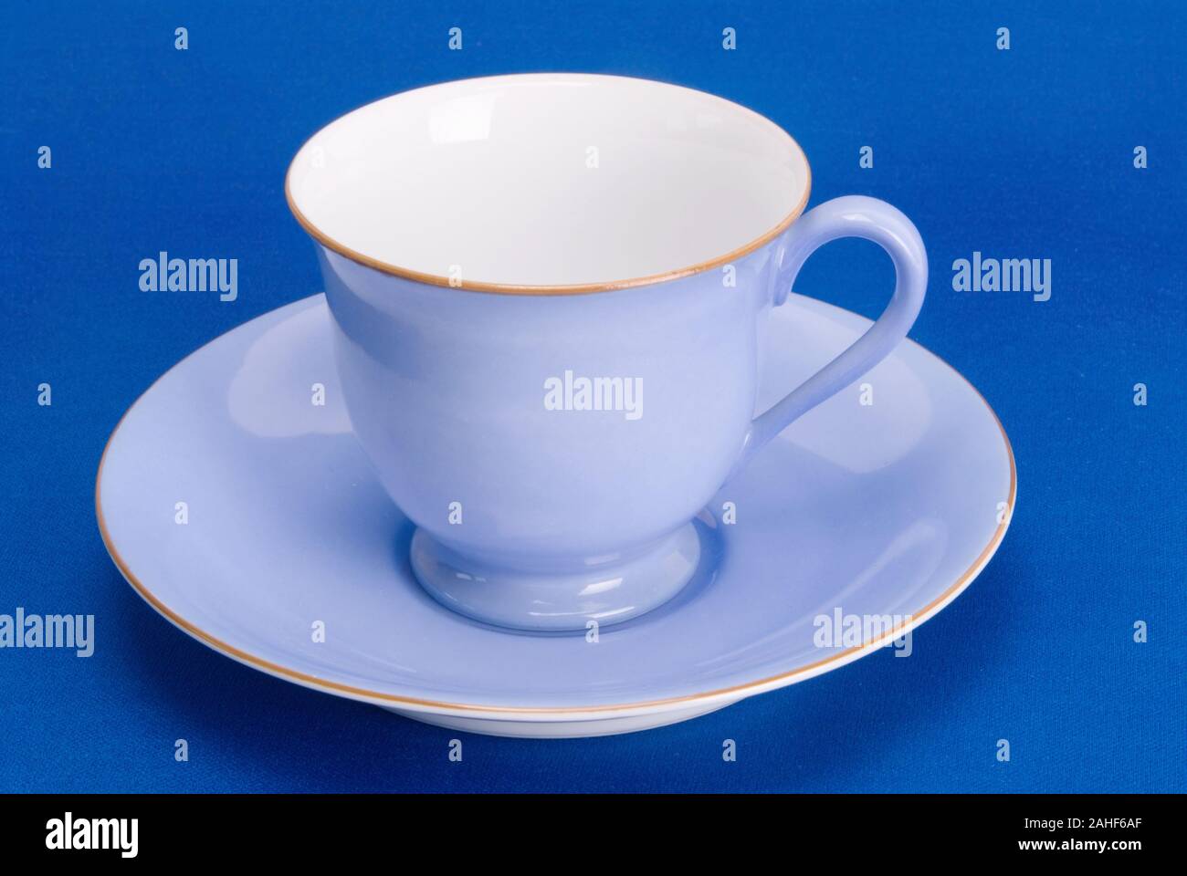 antique blue and white cup with a matching saucer on a textured blue