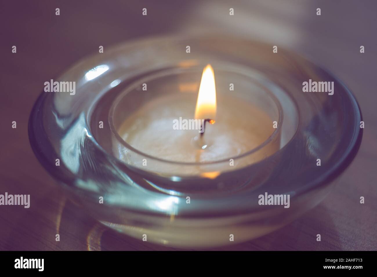 low candle burns in a round glass candlestick, closeup Stock Photo Alamy