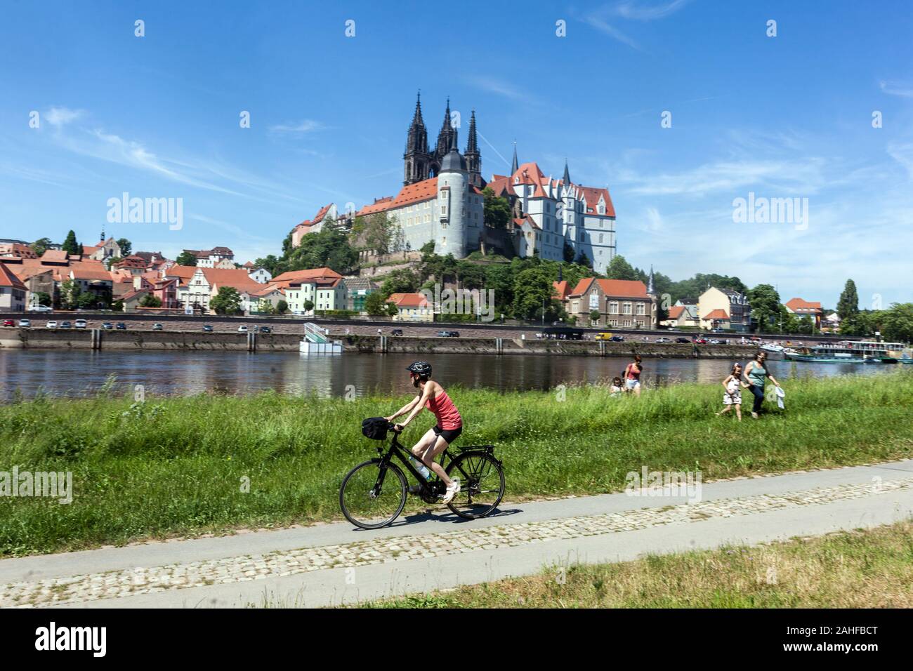People on a meadow at the Elbe river bike, Teenager riding a bicycle on Germany cycle path Meissen skyline Saxony Germany Elberdweg Riding bike Stock Photo