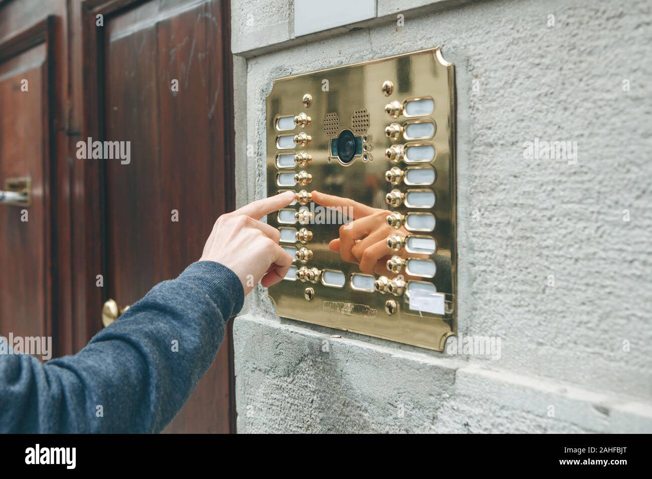 A male hand presses a doorphone button for access inside. Stock Photo