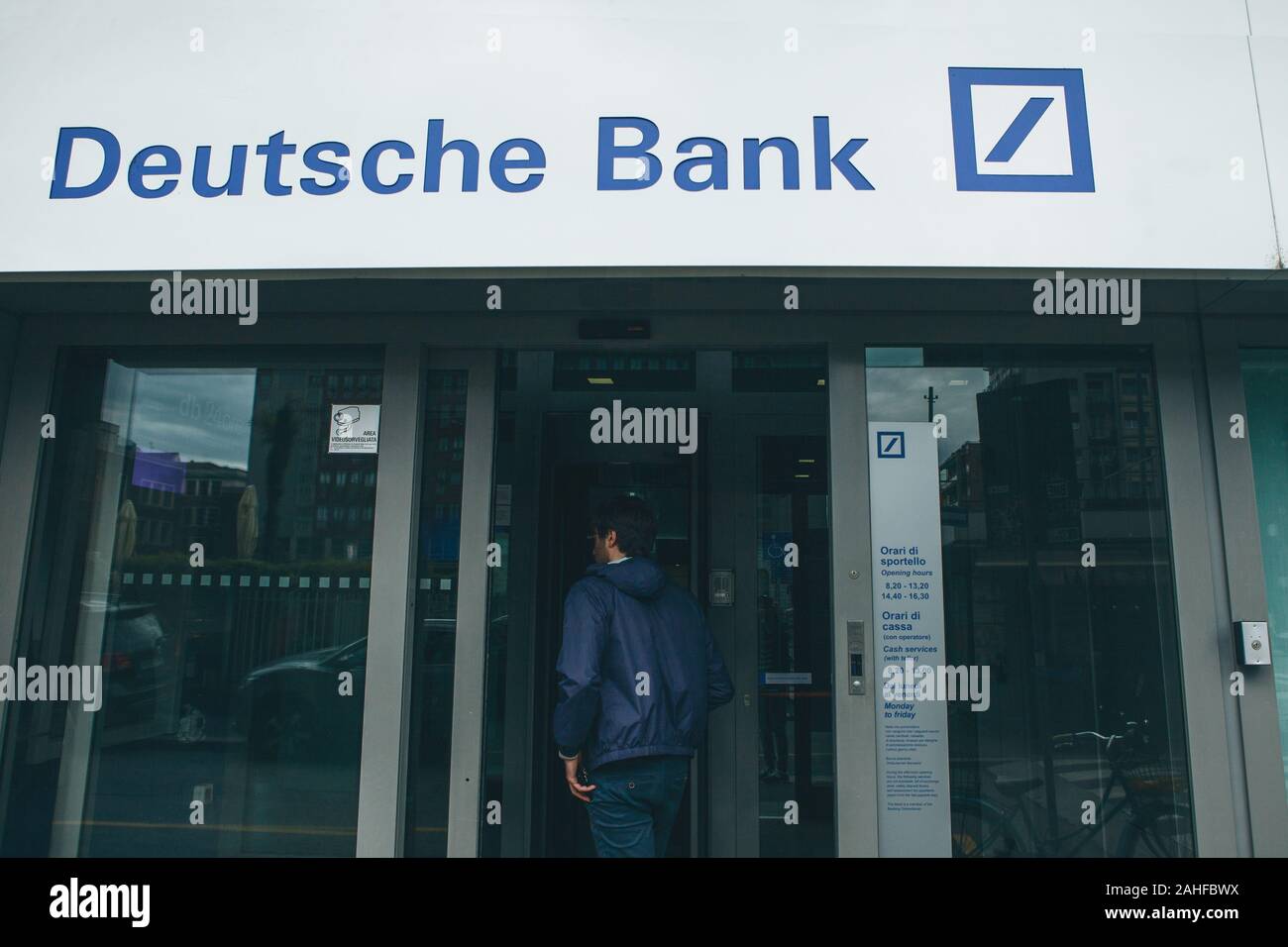 Italy, Milan, May 30, 2019: A man enters the door inside the German Deutsche Bank. Financial institution. Stock Photo