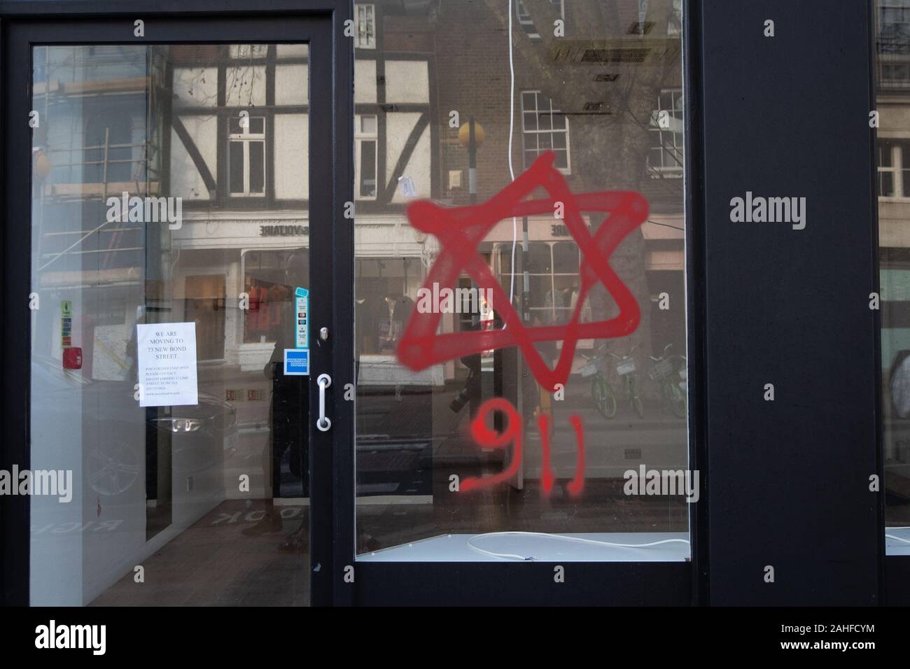 Anti-semitic graffiti in the form of numbers, 9 11, and a Star of David, on a shop window in Belsize Park, North London. Stock Photo