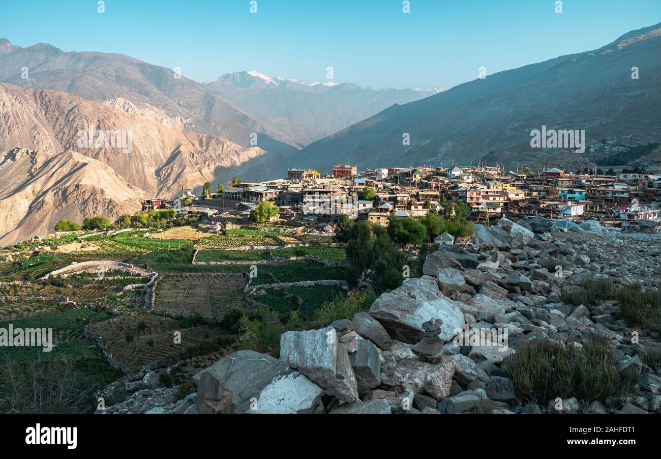 Nako village flanked by fields, high Himalayan mountains, and rocky footpath in the Spiti valley at sunrise in Himachal Pradesh, India. Stock Photo