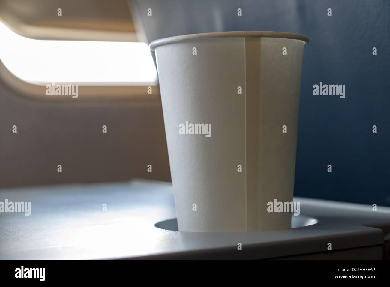 Paper cup with drink on board in flying aircraft. Refreshment drink on ...