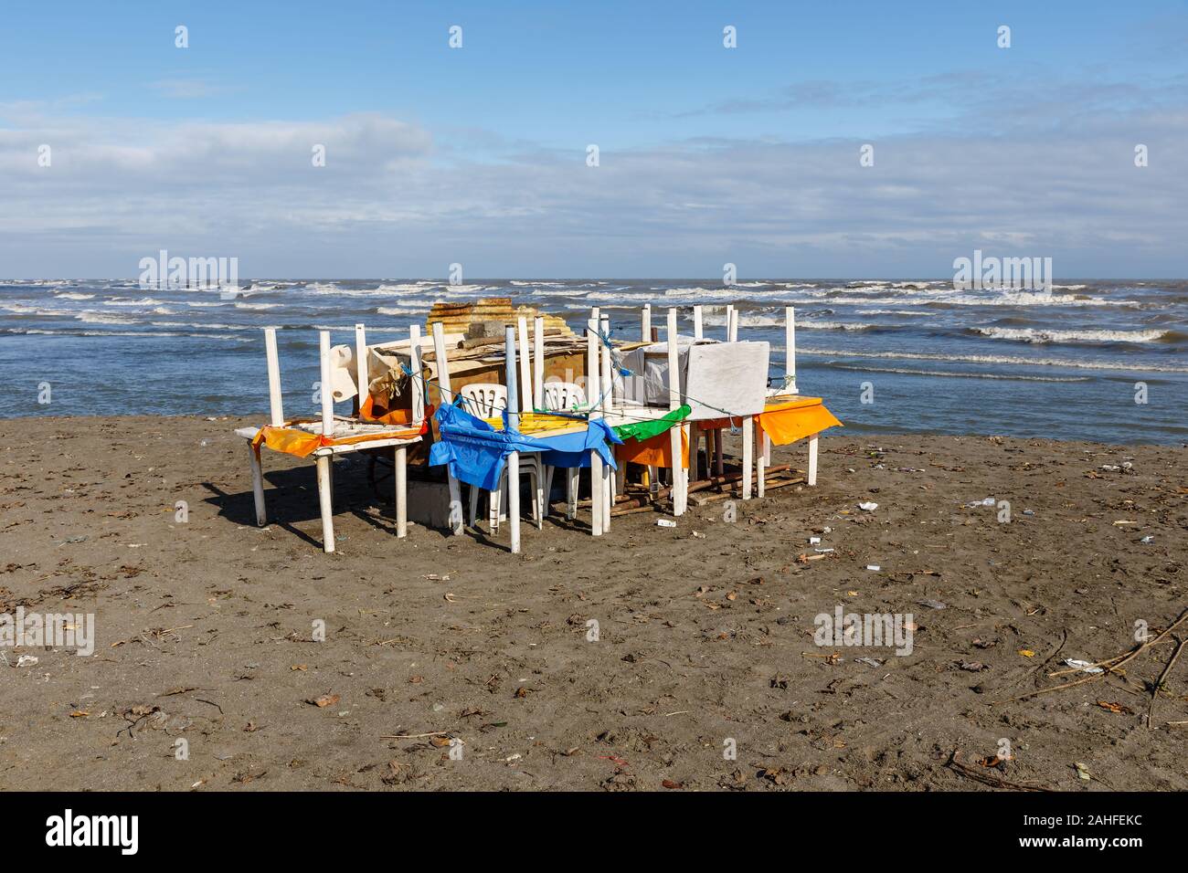 plastic tables and chairs stacked on the sandy seashore before the storm, storm protection Stock Photo