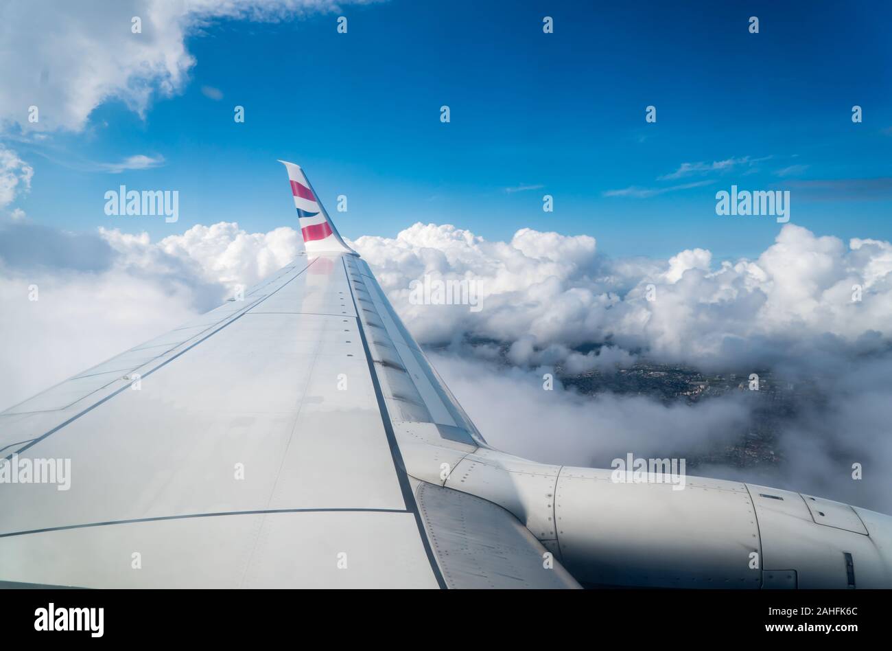 British airways, Comair winglet logo on fixed wing of an airplane flying above the clouds and in blue sky above land in Mauritius Stock Photo