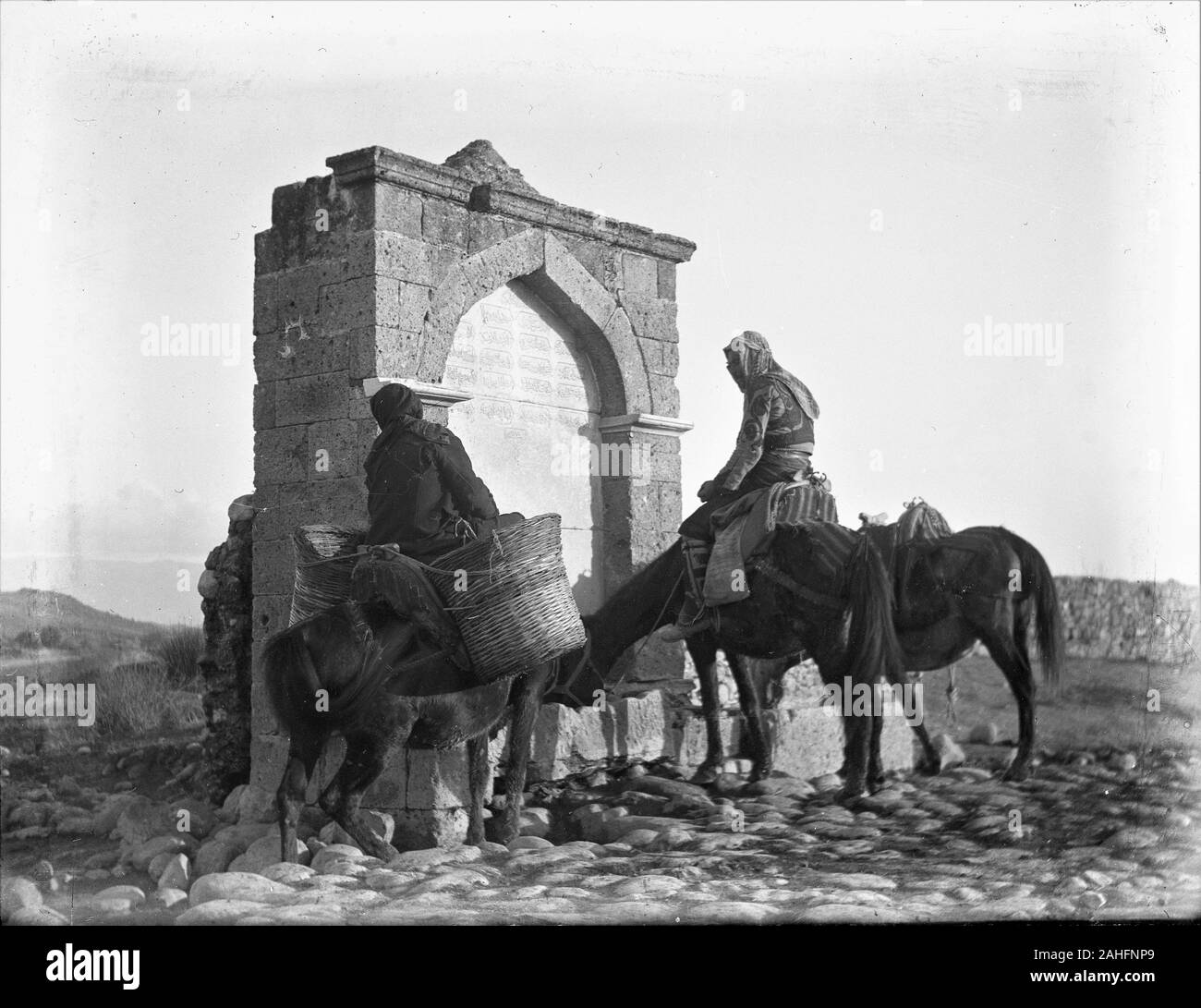 Turkey Ottoman countrymen in traditional customes soaking their horses at a public 'Menzil' fountain. These Menzils were located outside settlements and served caravans, travellers, farmers and their beasts. The fountains had inscriptions in verses, with the last line giving information about the construction date, either directly or in Ebced calculation Copy from a dry glass plate, originating from the Herry W. Schaefer collection. Stock Photo