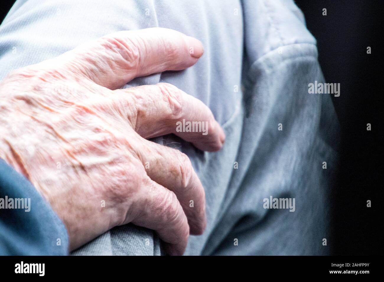 A close up of an elderly person's hand resting on their leg Stock Photo